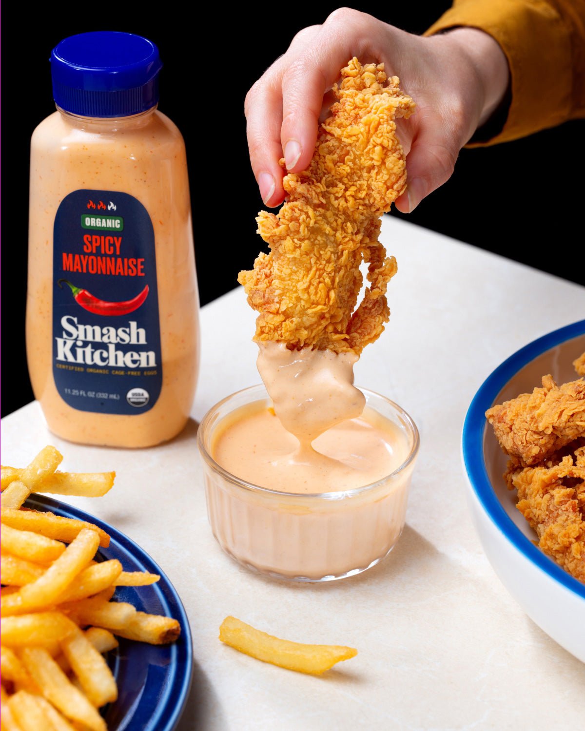 Dipping chicken fingers into Smash Kitchen Spicy Mayonnaise